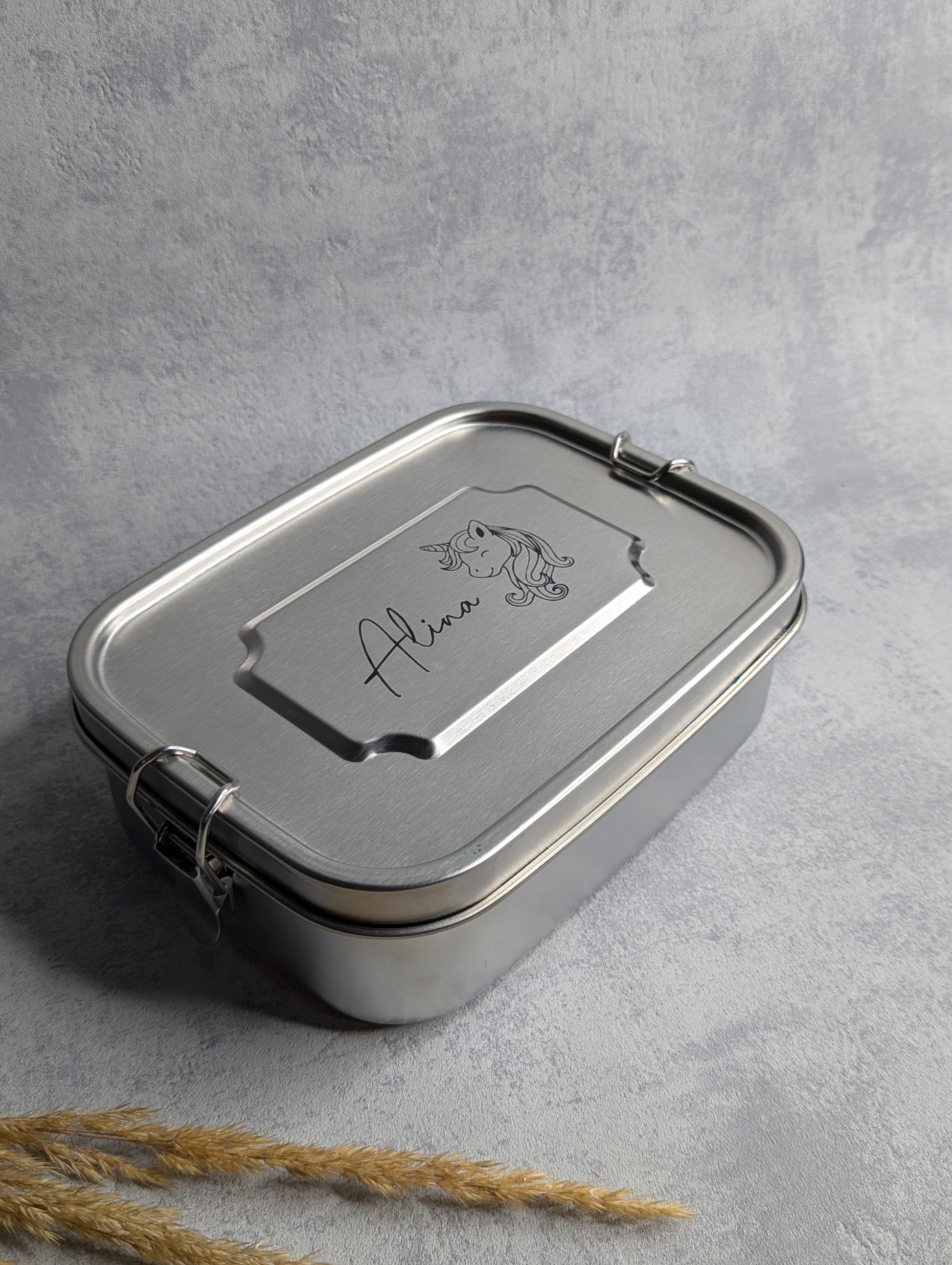 Personalisierte Edelstahl-Lunchbox mit sicherem Clip-Verschluss und individueller Gravur. Die Brotdose trägt den Namen 'Alina' sowie ein Einhorn-Motiv. Nachhaltige, BPA-freie Vesperbox für Schule, Arbeit oder unterwegs. Robustes Design für eine umweltfreundliche Alternative zu Plastikbehältern.