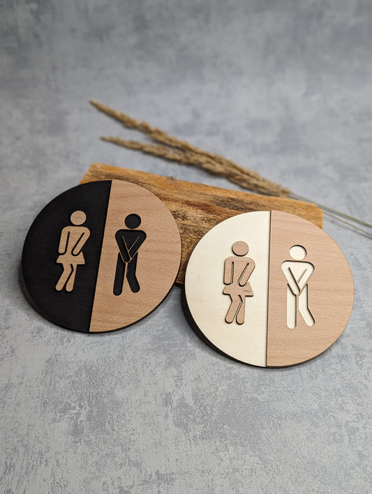 Rundes Toilettenschild aus Holz mit stilisierter Damen- und Herrenfigur, lasergraviert und in zwei Farbvarianten erhältlich.