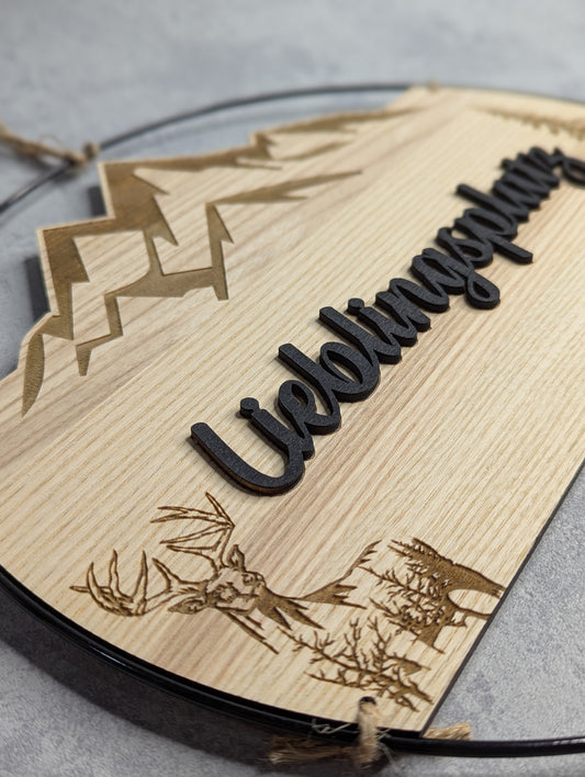 Rechteckiges Holzschneidebrett aus hellem Holz mit eingraviertem Schriftzug 'Überraschung' und dekorativen Hirsch-Motiven am unteren Rand