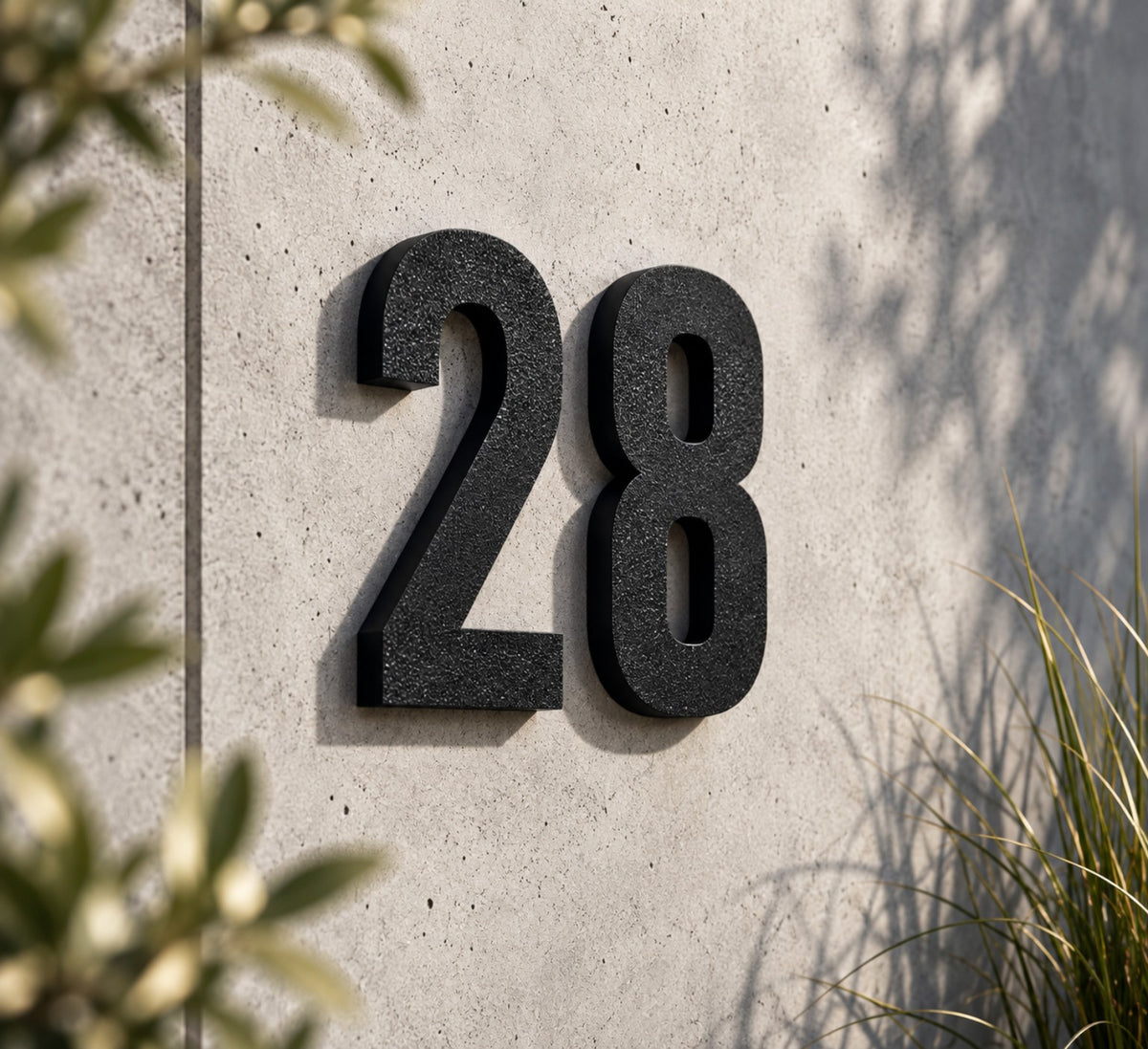 Schwarze 3D-Hausnummer 28 an einer modernen Betonwand im Außenbereich
