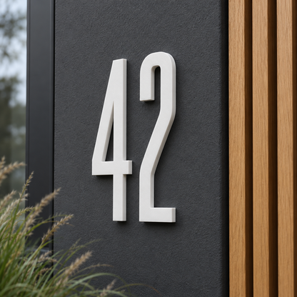 Weiße 3D-Hausnummer 42 in schmaler moderner Schrift auf dunkler Fassade – Gestaltungsbeispiel