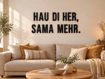 Österreichischer Dialektspruch „HAU DI HER, SAMA MEHR.“ aus schwarzen 3D-Buchstaben über einem beigen Sofa