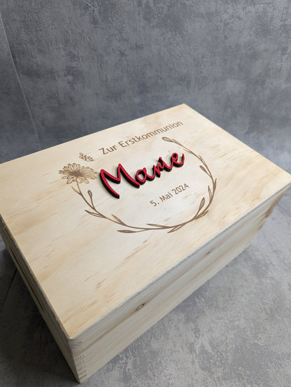 Personalisierte Holz-Erinnerungsbox zur Erstkommunion mit graviertem Blumenkranz, Datum und rotem 3D-Namen auf dem Deckel.