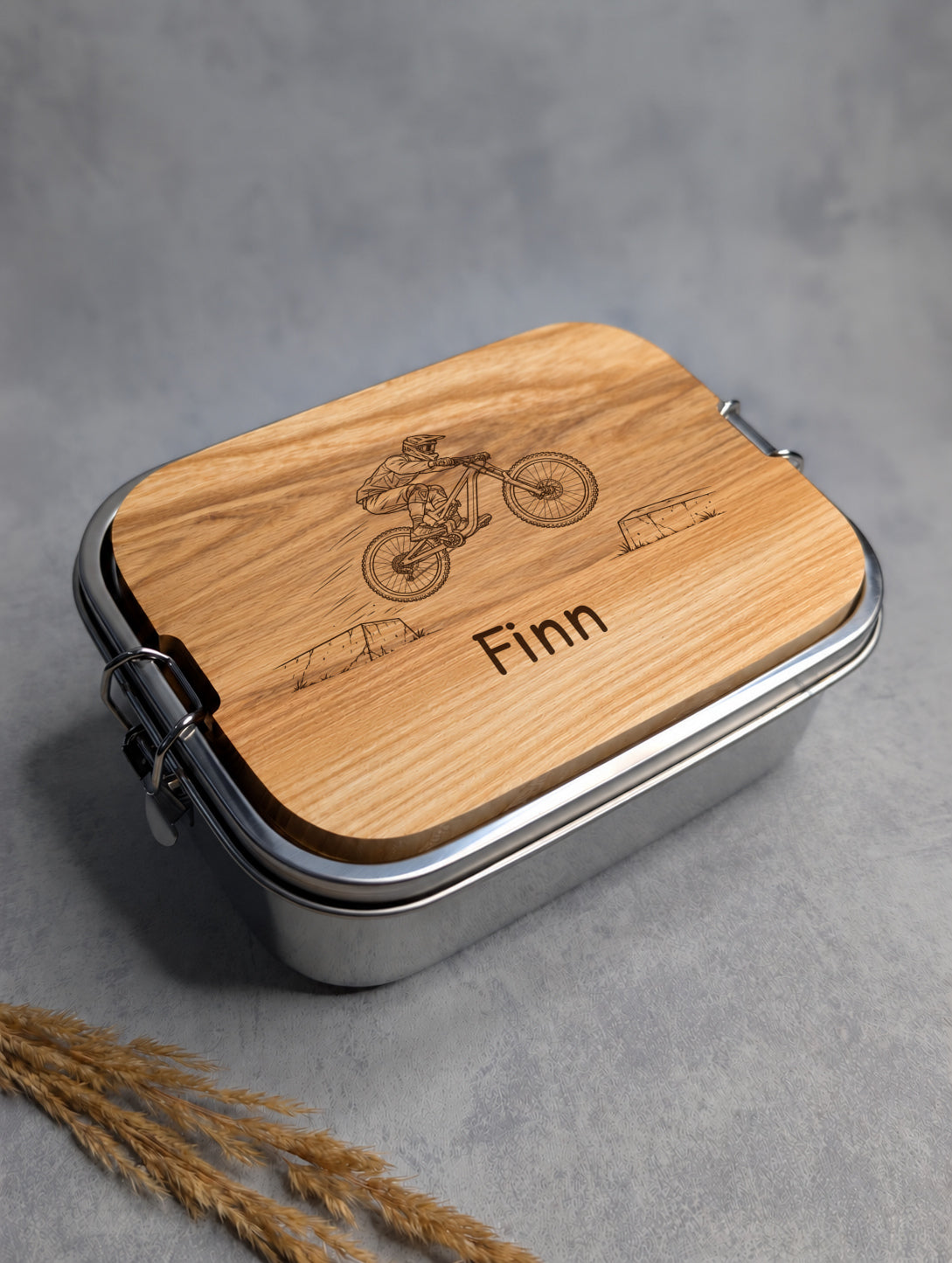 Geschlossene Edelstahl-Lunchbox mit Mountainbike-Comicgravur und dem Beispielnamen Finn in Patrick Hand