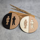 Rundes Toilettenschild aus Holz mit stilisierter Damen- und Herrenfigur, lasergraviert und in zwei Farbvarianten erhältlich.